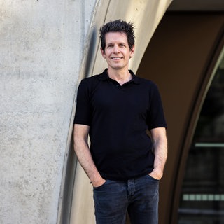Martin Andree, Medienwissenschaftler, lehnt mit der Schulter an einer Betonwand.