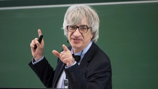 Physiker Metin Tolan lächelt in die Kamera, während er etwas erklärt. Physiler Metin Tolan lächelt in die Kamera. DER SPIEGEL schrieb über Metin Tolan: "Deutschlands womöglich coolster Physikprofessor". Klar, denn er kann sogar die Spur des Weihnachtsmanns verfolgen und in SWR1 Leute von James Bond bis Star Trek alles physikalisch erklären.