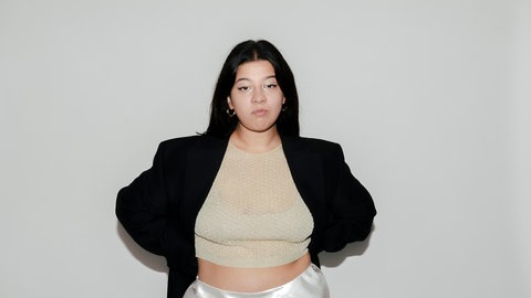 Yasmine M’Barek, Journalistin und Autorin, hat ihre Arme hinter dem Rücken und schaut in die Kamera.