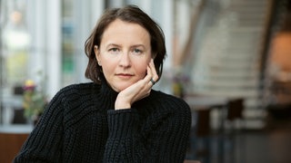 Schriftstellerin Alina Bronsky stützt ihren Kopf mit der Hand und schaut in die Kamera.
