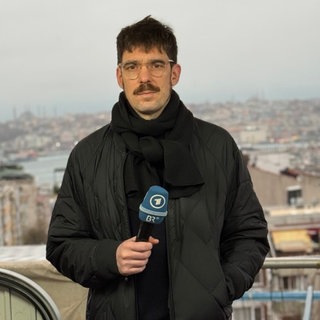 ARD-Korrespondent Benjamin Weber hält ein Mikrofon in der Hand und schaut in die Kamera.  Die Massenproteste im Iran gegen das Mullah-Regime wurden brutal niedergeschlagen. ARD-Korrespondent Benjamin Weber schätzt in SWR1 Leute die Lage vor Ort und die Zu