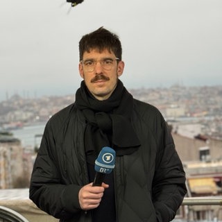 ARD-Korrespondent Benjamin Weber hält ein Mikrofon in der Hand und schaut in die Kamera.  Die Massenproteste im Iran gegen das Mullah-Regime wurden brutal niedergeschlagen. ARD-Korrespondent Benjamin Weber schätzt in SWR1 Leute die Lage vor Ort und die Zukunft des Iran ein.