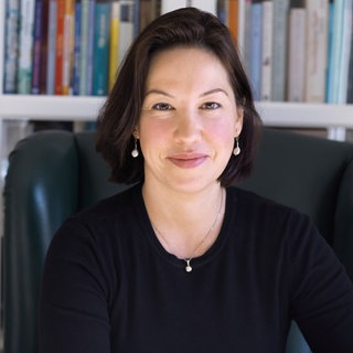 Journalistin Ceyda Nurtsch sitzt vor einem Bücherregal und schaut freundlich in die Kamera.