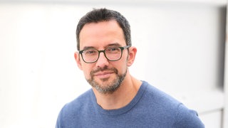 Chefredakteur Finanztip, Saidi Sulilatu, lächelt in die Kamera. In SWR1 Leute spricht er über Finanzen, Geldanlage, sparen, ETFs, Aktien und Vermögensaufbau.