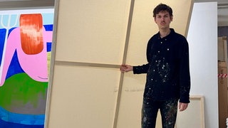 Künstler Carlo Krone steht bei Bildern.