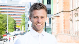 Patrick Kaczmarczyk blickt in die Kamera. Der Politökonom fordert ein Umdenken in der Wirtschaftspolitik zwischen Industriestaaten und dem globalen Süden. Er ist zu Gast in SWR1 Leute