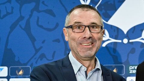 Jörg Albrecht, Ex-Präsident der TSG 1899 Hoffenheim, lacht während einer Pressekonferenz in die Kamera.