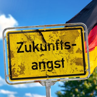 Fotomontage, Ein altes Schild mit der Aufschrift Zukunftsangst vor deutscher Flagge symbolisiert die wachsende Unsicherheit vieler Menschen. Die Nachhaltigkeitsforscherin Maike Sippel findet: Wir sollten selbst die Initiative ergreifen, statt auf Weiche
