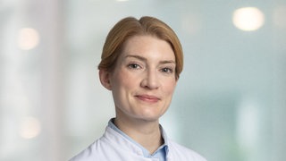 Transgender-Chirurgin Isabella Kurth steht in weißem Arztkittel da.