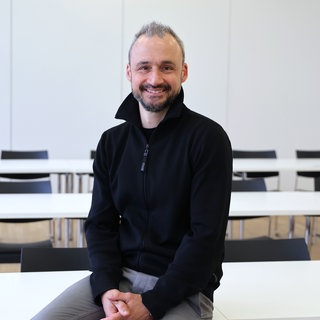 Gesundheitsökonom Jan-Marc Hodek lacht in die Kamera. In SWR1 Leute spricht er über die GKV-Reform.