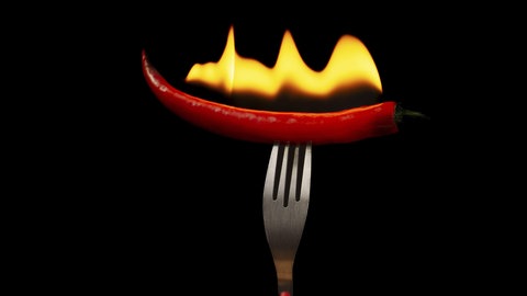 Eine brennende Chili auf einer Gabel. Mehr Schärfe ist einer der zehn Hacks, die den Stoffwechsel ankurbeln