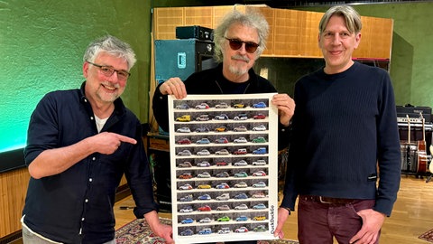 Meilensteine-Host Frank König und SWR1 Musikredakteur Benjamin Brendebach zusammen mit BAP-Frontmann Wolfgang Niedecken | 50 Jahre BAP – "Paar Daach Spääder"