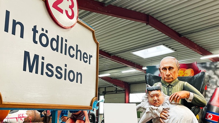 Der russische Präsident WladimirPutin sitzt auf einer Art Thron und hat eine langhaarige Katze auf dem Schoß, die das Gesicht des nordkoreanischen Machthabers Kim Jong-un hat.