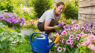 Eine Frau freut sich über Blumen im Garten | Der richtige Zeitpunkt zum Gießen