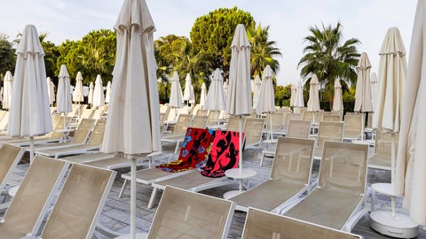 Zwei bunte Handtücher dienen als Reservierung auf Liegestühlen am Pool | Kuriose Regeln in Urlaubsländern