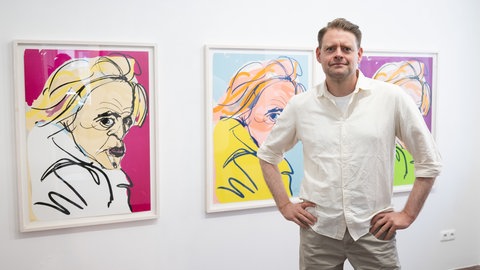 Max Giermann steht in der Galerie Holger John vor seinen Kunstwerken «Kinski». Die Bilder sind Teil seiner Ausstellung «Dann mal doch, du dumme Sau!».