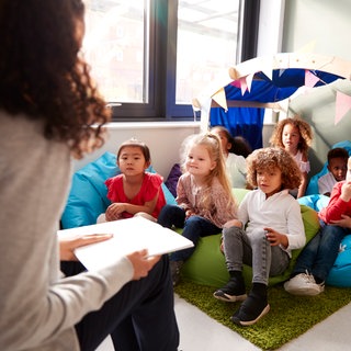 Eine Frau liest Kindern aus einem Buch vor
