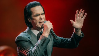 "Murder Ballads" und "Murder Look": Es ist der typische Look von Nick Cave: Der maßgeschneiderte Anzug, glänzende Lackschuhe und dazu die nach hinten gestylten, schwarzgefärbten Haare.