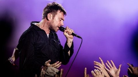 Das musikalische Mastermind hinter der Band Gorillaz ist Blur-Frontmann Damon Albarn. Hier bei einem Livekonzert der Gorillaz beim Roskilde Festival in Dänemark 2018.
