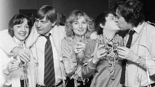 70er-Jahre: Männer und Frauen feiern mit Getränken und Luftschlangen Silvester