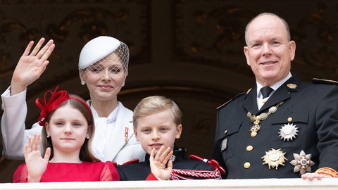 Fürstin Charlène von Monaco steht gemeinsam mit ihren Kindern Jacques und Gabriella sowie mit ihrem Mann Albert auf einem Balkon und winkt, denn es ist monegassischer Nationalfeiertag.