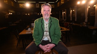 Schauspieler Hansi Kraus sitzt auf der Bühne im Augustiner Stammhaus