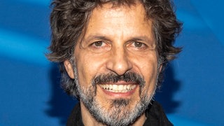 Der Schauspieler Pasquale Aleardi schaut lächelnd in die Kamera.
