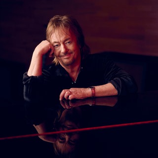 Chris Norman sitzt am Flügel und hat seinen Kopf in die Hand gestützt