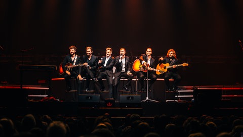BeeGees by MainCourse sitzen auf Barhockern auf der Bühne