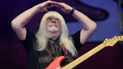 Andy Scott, Sänger von The Sweet, steht auf der Bühne und hebt die Hände zu einem Herz