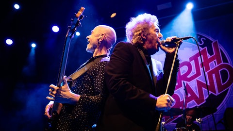 Die Band Manfred Manns Earth Band mit Musiker Robert Hard und Steve Kinch sind auf der Bühne, stehen Rücken an Rücken und singen