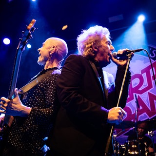 Die Band Manfred Manns Earth Band mit Musiker Robert Hard und Steve Kinch sind auf der Bühne, stehen Rücken an Rücken und singen