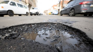 Eine Straße mit Schlagloch, Symbolbild für Artikel "Mehr Risse und Schlaglöcher nach dem Winter in Rheinland-Pfalz"