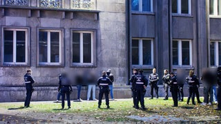 Mehrere Polizisten umzingeln am Stadthaus in Mainz eine Gruppe Männer, die einen Polizisten angegriffen haben soll.