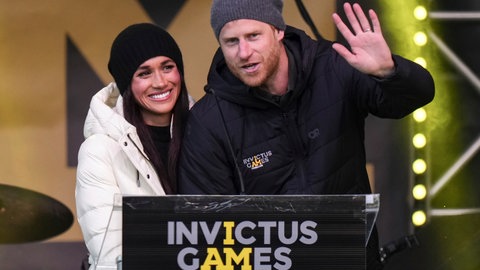 Prinz Harry und seine Frau Meghan sind gut gelaunt bei den Invictus Games in Kanada und winken in die Kamera.