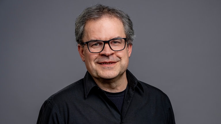 Porträt von SWR4 Moderator Holger Bentzien, lächelnd im schwarzen Hemd