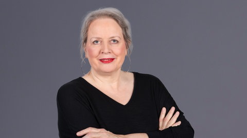 SWR4 Moderatorin Barbara Scherrer in schwarzem Oberteil vor grauem Hintergrund. 