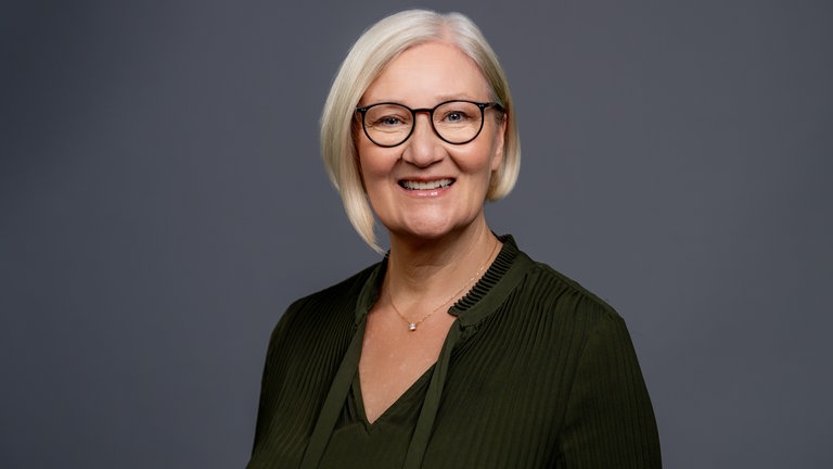 Porträt der lächelnden SWR4 Moderatorin und Redakteurin Iris Kruse in olivefarbenen Oberteil