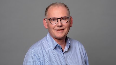 Porträt des lächelnden SWR4 Moderators Hans-Jürgen Finger in hellblau gemustertem Hemd