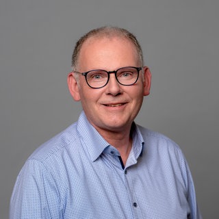 Porträt des lächelnden SWR4 Moderators Hans-Jürgen Finger in hellblau gemustertem Hemd