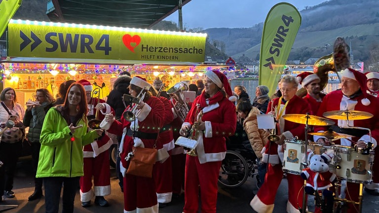 Weihnachtsmarkt Traben-Trarbach: Der SWR4 Adventszauber war mit seinem Adventsmobil dabei und nebenan spielte eine Kapelle in Weihnachtsmannkostümen Musik.