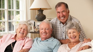 Senioren auf einem Sofa in ihrer WG: Die Renterinnen leben und lachen zusammen.