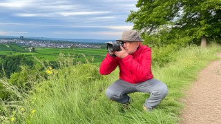 Unterwegs im Südwesten – SWR4 Ausflugstipps: Moderator Stefan Nink fotografiert vor grüner Landschaft.