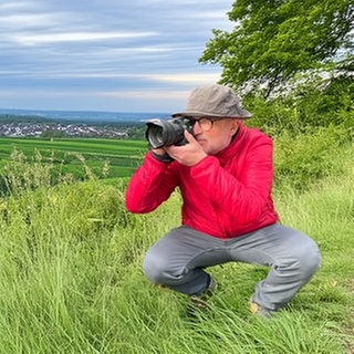 Unterwegs im Südwesten – SWR4 Ausflugstipps: Moderator Stefan Nink fotografiert vor grüner Landschaft.