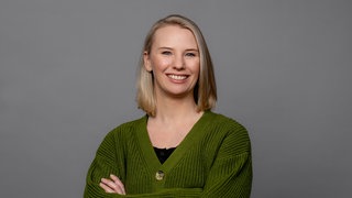 Julia Schönleber trägt eine grüne Strickjacke und lacht direkt in die Kamera