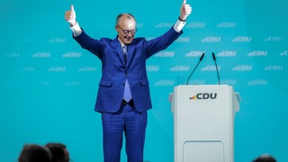 Friedrich Merz, Kanzlerkandidat der Union und CDU-Bundesvorsitzender, winkt bei einer Parteiveranstaltung mit den Daumen nach oben ins Publikum.