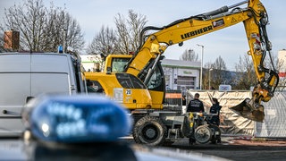 Ein Bagger steht nach einer Zerstörungsfahrt neben einem Autohaus in Tauberbischofsheim . Nach der zerstörerischen Baggerfahrt und tödlichen Polizeischüssen auf den Fahrer im Nordosten Baden-Württembergs laufen die Ermittlungen zu dem Geschehen.
