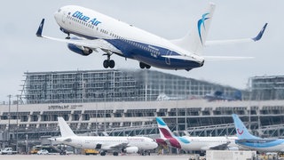 Ein Flugzeug der Fluggesellschaft Blue Air startet am Flughafen Stuttgart, dahinter ist Terminal 1 des Flughafens zu sehen.