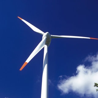 Windrad vor blauem Himmel.