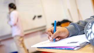 Nahaufnahme Hand: Schüler macht sich im Unterricht Notizen